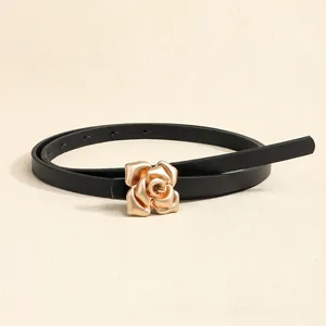Close-up of matte gold rose buckle on a slim black leather fashion belt for women