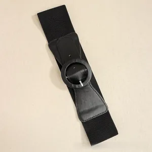 Detail view of the black elastic wide belt featuring a large round buckle and PU leather ends