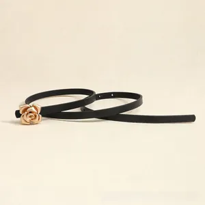 Detailed close-up of a rose gold flower buckle on a sleek black leather waist belt