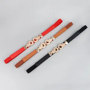 Detail showing gold twist buckle on red, brown, and black elastic belts for dresses