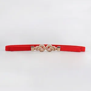 Detail of red elastic waist belt with gold textured double knot buckle and leather patches