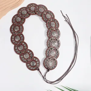 Detail of bohemian brown leather disc belt with vintage metal studs and lace-up closure