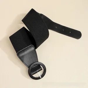 Close-up of black elastic wide waist belt featuring a round buckle and faux leather trim
