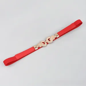 Detailed close-up of a red elastic waist belt featuring a gold double-ring buckle with texture