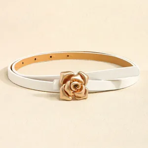 Close-up of golden rose-shaped buckle on white leather belt with polished metal finish