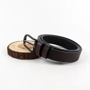 Close-up of a dark brown leather belt with a sleek gunmetal pin buckle on wood