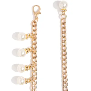 Detail view of gold chain belt featuring large imitation pearls with rhinestone rings
