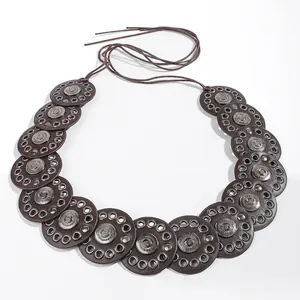 Detail of bohemian dark brown leather belt with embossed metal discs and eyelets