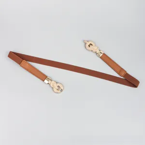 Detail of tan elastic waist belt featuring a vintage gold snake-patterned metal buckle