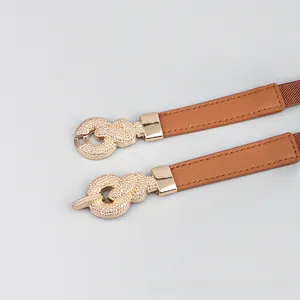 Detail of interlocking gold alloy buckle with textured finish on a slim elastic belt