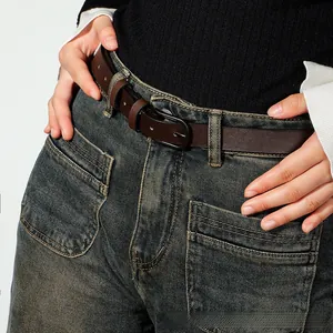 Close-up of a minimalist dark brown leather belt with black buckle on vintage denim