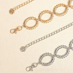 Dettaglio di maglie di catena in metallo oro e argento con chiusura a moschettone e fiori