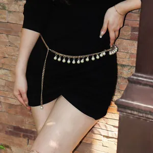 Detail of elegant gold metal waist chain with white faux pearls on black dress