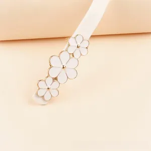 Détail de la ceinture blanche en PU ornée de trois fleurs blanches au centre doré