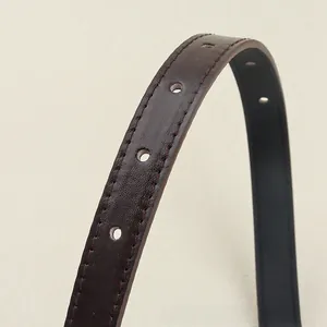 Détail d'une ceinture en cuir marron avec surpiqûres rouges et trous de réglage