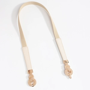 Detail of golden interlocking buckle on elastic beige waist belt for women dresses
