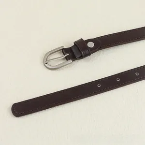 Détail d'une ceinture en cuir marron foncé avec boucle mate argentée et coutures renforcées