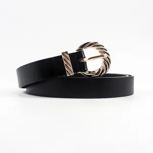 Detail of minimalist black leather belt with golden spiral textured round buckle decoration