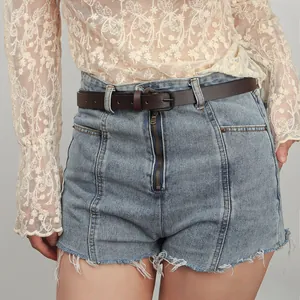 Detail of high-waisted light blue denim shorts with frayed hems and a slim brown belt