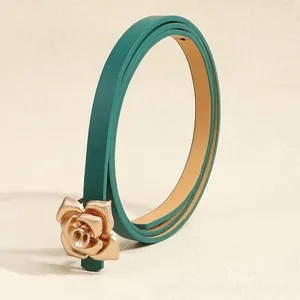 Macro view of dark green leather belt with elegant matte gold rose flower buckle