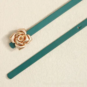 Detail of dark green leather belt featuring a matte gold rose floral buckle with texture