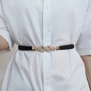 Detail view of a black leather skinny belt with a gold interlaced rope knot buckle on a shirt