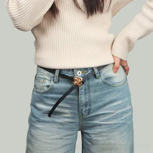 Detail of elegant black slim belt with a vintage golden 3D rose buckle on blue jeans