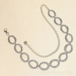 Dettaglio della catena da vita in metallo argento con maglie a spirale e pendente a rosa