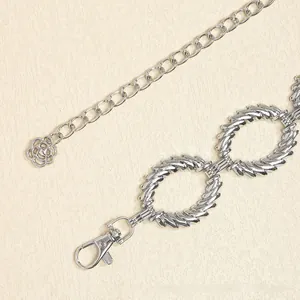 Dettaglio di una catena da vita in metallo argento con anelli testurizzati e ciondolo