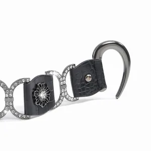 Détail d'une ceinture en cuir crocodile avec boucle fleurie ornée de strass brillants