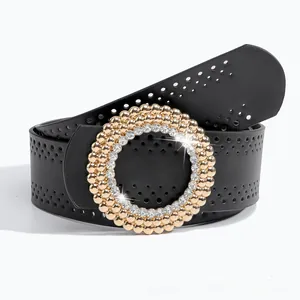 Détail d'une ceinture en cuir noir avec grande boucle dorée, strass et perforations