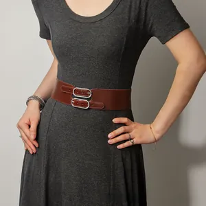 Détail d'une large ceinture en cuir marron vintage avec double boucle argentée sur une robe