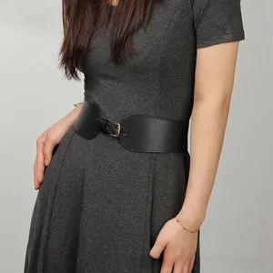 Gros plan d'une large ceinture élastique noire avec boucle dorée sur une robe grise