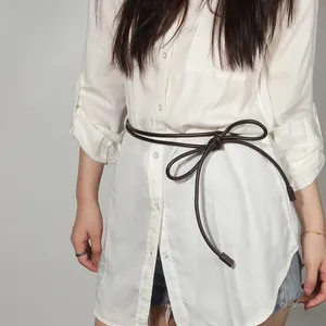 Close-up of a dark brown knotted waist rope tied on a white long shirt for styling
