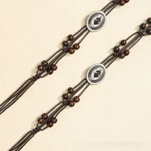Detailed macro of ethnic braided waist rope with silver metal totems and dark wood beads