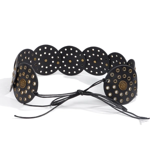 Detail of bohemian black leather belt with gold rivets and embossed metal buckle