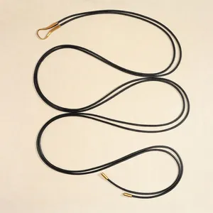 Ceinture fine noire de style ethnique avec embouts en métal doré sur fond texturé