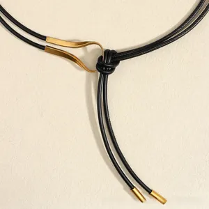 Détail de cordons en cuir noir avec une boucle métallique dorée au design épuré