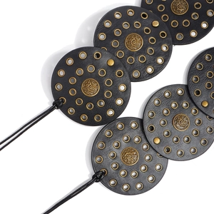 Detailed close-up of bohemian leather belt with metal eyelets and brass rivet accents