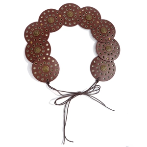 Close-up of bohemian leather belt with metal studs and vintage medallions on white background