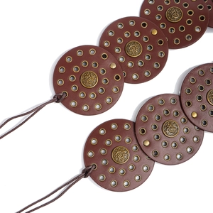 Close-up of bohemian brown leather belt with antique dragon carvings and metal eyelets
