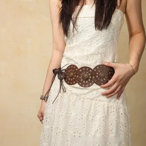 Detail of bohemian brown leather belt with metal eyelets and vintage metal medallions