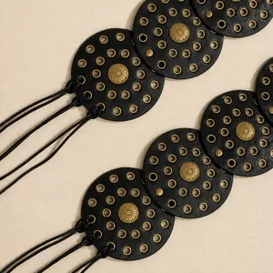 Close-up of bohemian leather belt with gold metal eyelets and sunflower rivets