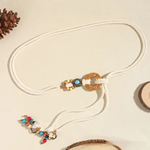 Détail de la ceinture tressée avec boucle en bois et perles bohèmes sur fond texturé