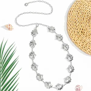 Chaîne de taille élégante en métal argenté avec pendentifs coquillages sur fond de plage