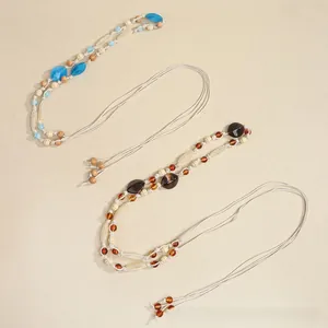 Detail view of Bohemian woven beaded necklaces with tassels in blue and amber tones
