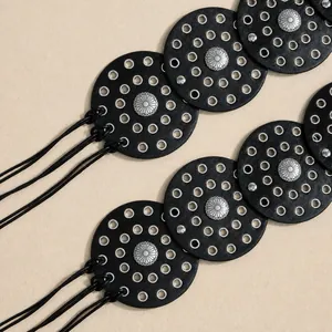 Detail of bohemian black leather belt with silver eyelets and sunburst flower rivets
