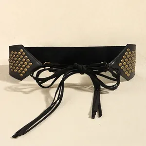 Detail of black corset belt featuring gold cone studs and elegant ribbon tie closure