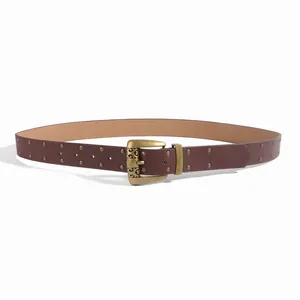 Détail d'une ceinture en similicuir marron avec boucle en laiton gravée de fleurs