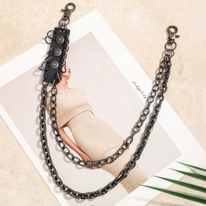 Detail of gun-black multi-layer punk pant chain with leather patches and studs